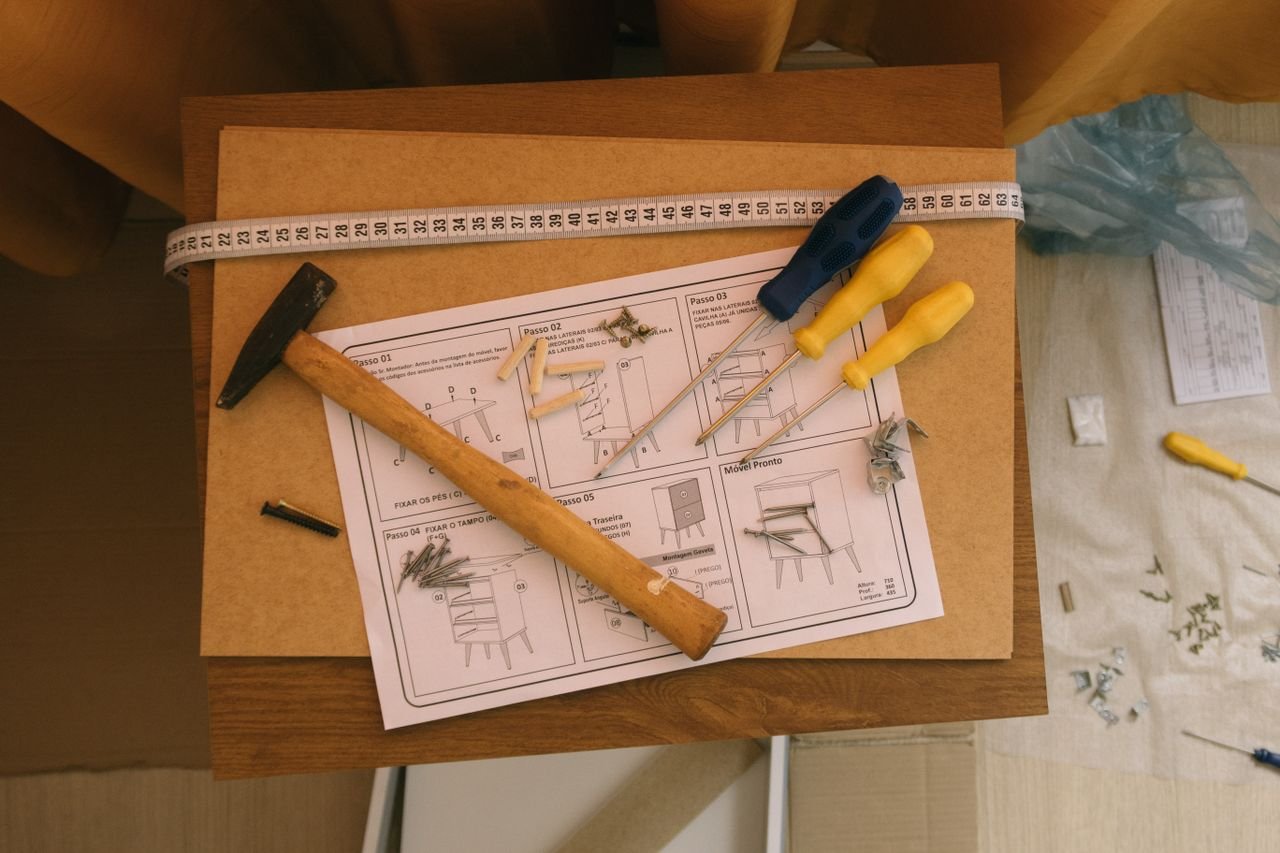 services-02 From above of paper instruction helping to assemble furniture with screwdrivers and hammer on top