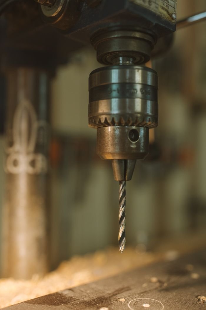 Detailed view of a drill press in an industrial setting, highlighting its metallic components.